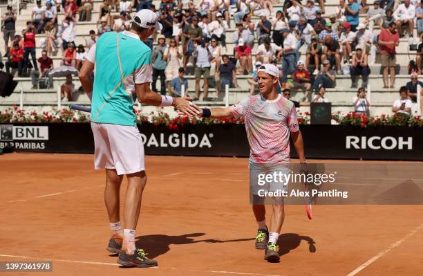 John Isner of the United States and Diego Schwartzman of Argentina celebrate winning the second set against Nikola Mektic and Mate Pavic of Croatia...