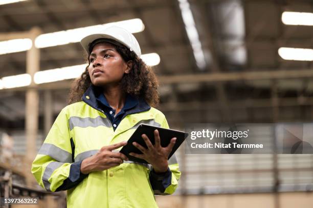 effectiveness of gender equality empowerment in manufacturing industry.  low angle view of a young african american woman engineer working in a manufacturing plant and is responsible for controlling, planning for the production process. - low motivation stock pictures, royalty-free photos & images
