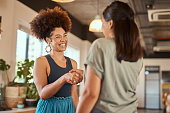 Beautiful mixed race creative business woman shaking hands with a female colleague. Two young female african american designers making a deal. A handshake to congratulate a coworker on their promotion