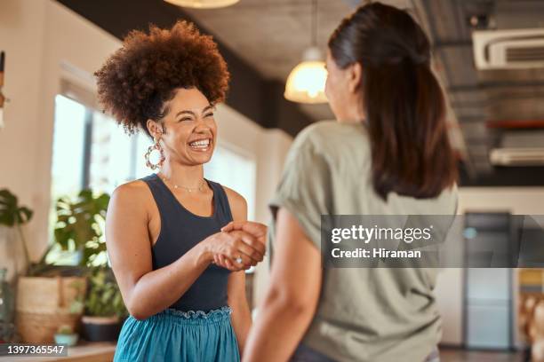 bela mulher de negócios criativa mestiça apertando as mãos de uma colega. duas jovens estilistas afro-americanas fazendo um acordo. um aperto de mão para parabenizar um colega de trabalho por sua promoção - parabenizar - fotografias e filmes do acervo