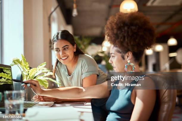 schöne gemischtrassige kreative geschäftsfrau, die einer weiblichen kollegin hilft. zwei junge afroamerikanische designerinnen unterhalten sich im büro. treffen zur diskussion und entwicklung einer erfolgsstrategie - mixed race young creatives in meeting stock-fotos und bilder