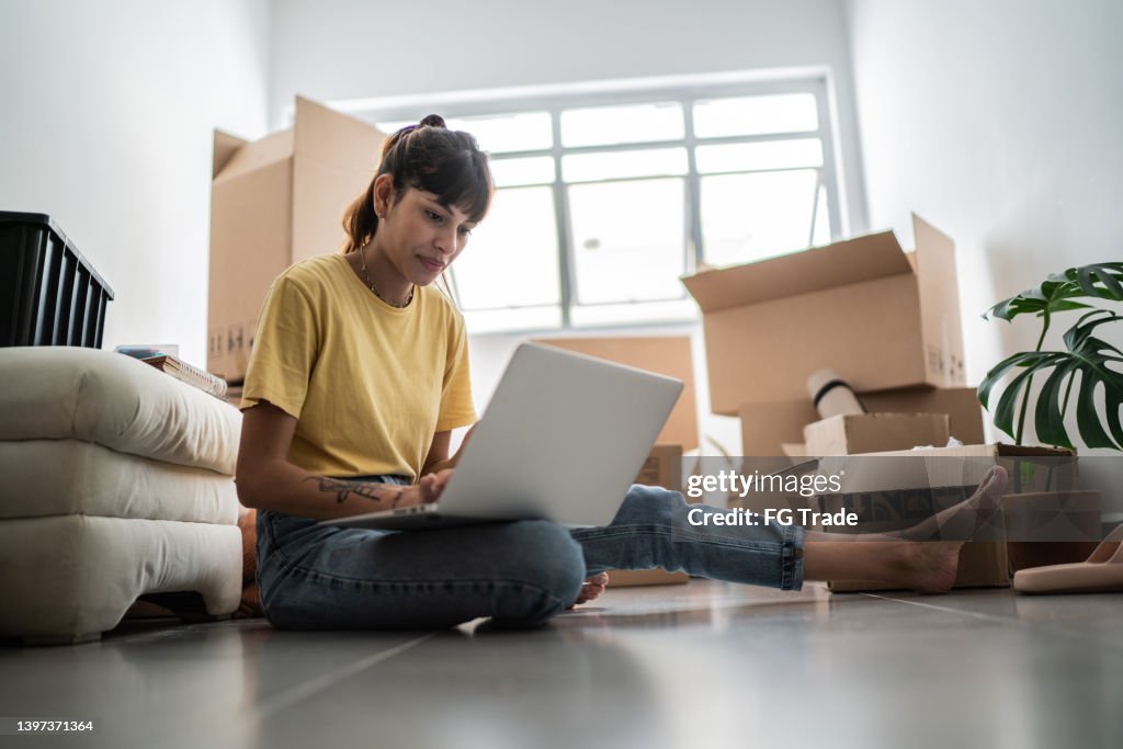 Mujer joven usando computadora portátil en casa nueva