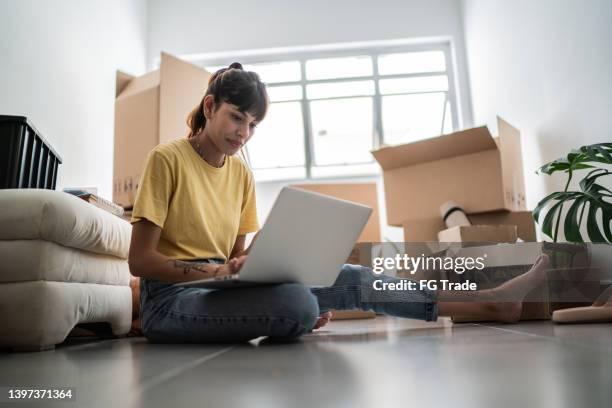 young woman using laptop at new house - women moving up stock pictures, royalty-free photos & images