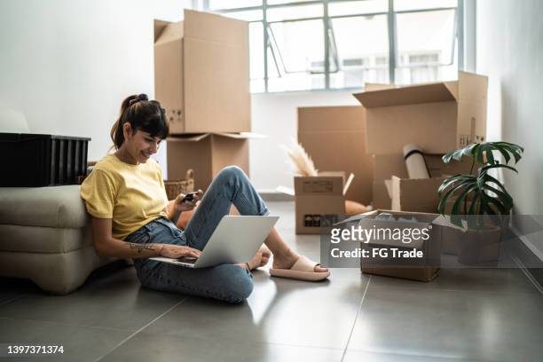 jeune femme faisant des achats en ligne pour une nouvelle maison - achat maison photos et images de collection