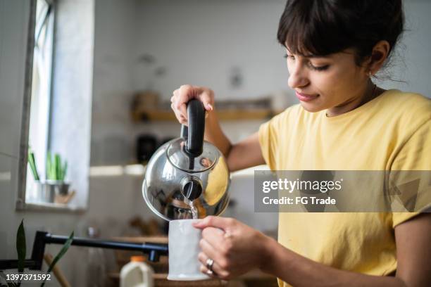 young woman preparing a tea at home - kettle stock pictures, royalty-free photos & images