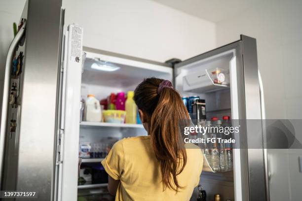 rückansicht einer jungen frau mit offener kühlschranktür - open fridge stock-fotos und bilder