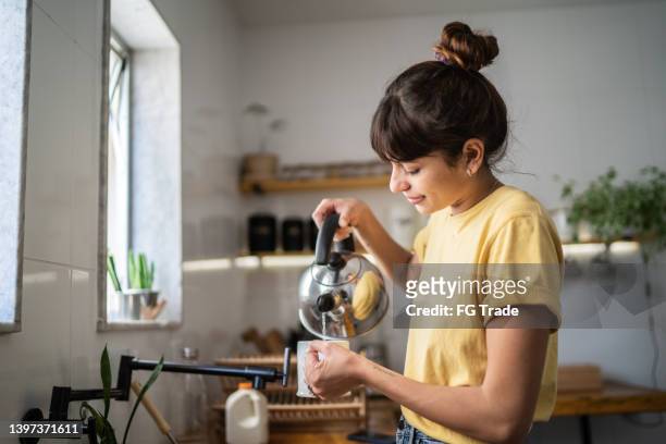 自宅でお茶を準備する若い女性 - ティーバッグ ストックフォトと画像