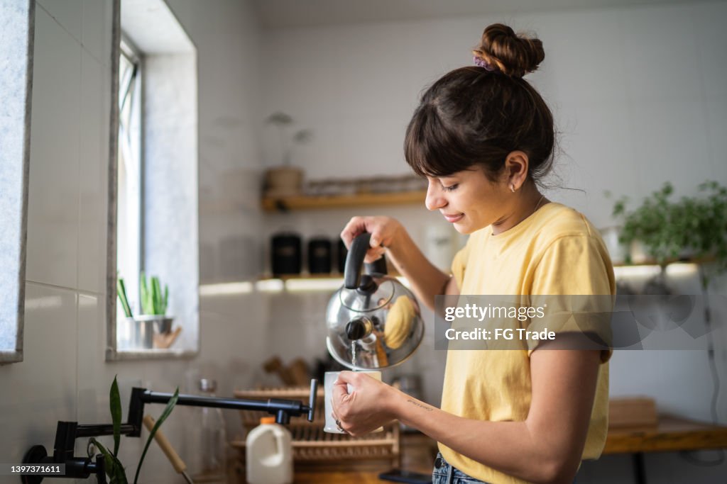Jovem mulher preparando um chá em casa