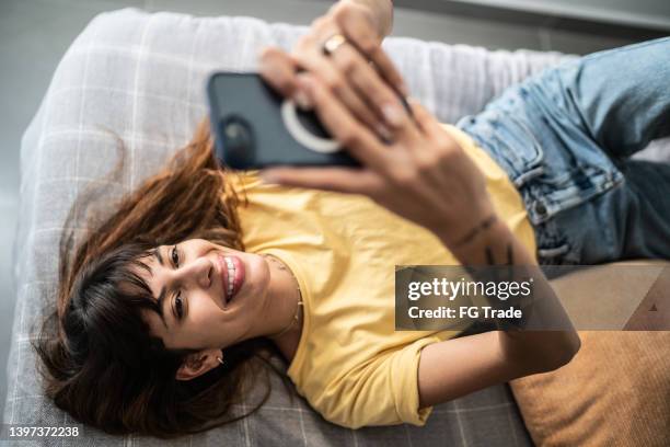 mujer joven usando el teléfono móvil en la cama de casa - tinder fotografías e imágenes de stock