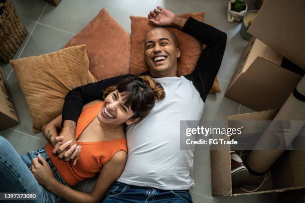 feliz pareja joven tirada en el suelo en una nueva casa - restarting fotografías e imágenes de stock