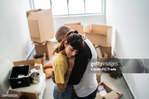 couple embracing leaving home - man with moving boxes authentic stockfoto's en -beelden
