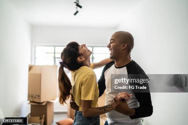 happy young couple dancing when moving house - young couple moving house stock pictures, royalty-free photos & images