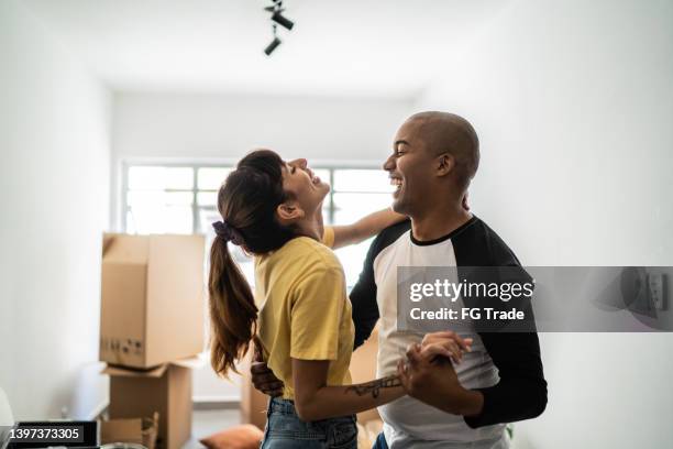 happy young couple dancing when moving house - celebrates firsts imagens e fotografias de stock