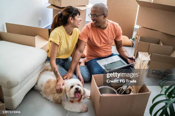 young couple packing and moving boxes at home - huurhuis stockfoto's en -beelden