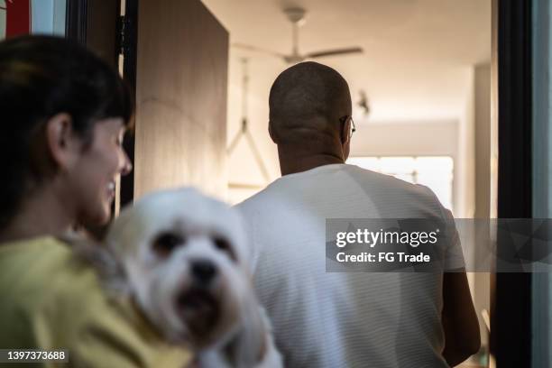 young couple entering at home - man opening door woman bildbanksfoton och bilder