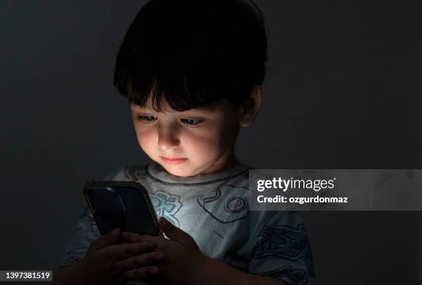 cute toddler boy playing with a smartphone - opening night of bb forever brigitte bardot the legend stockfoto's en -beelden