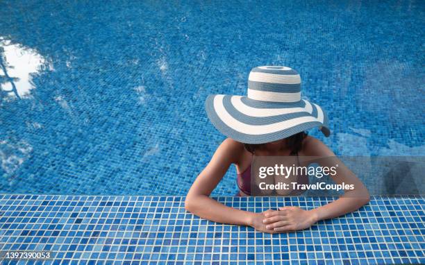 beautiful young woman in big straw hat in hot tub. women are relaxing at the poolside. woman relaxing in swimming pool spa. relaxing day in summer. summer luxury vacation - hot big women stockfoto's en -beelden