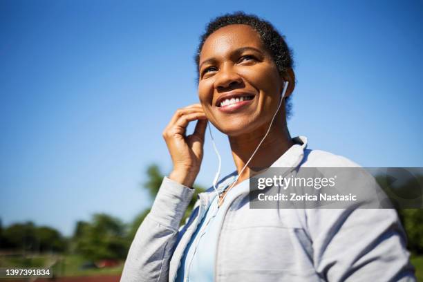 african-american woman with headphones smiling - activities in the sun stock pictures, royalty-free photos & images