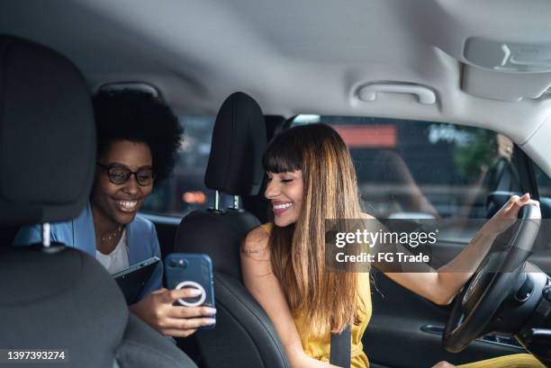 fahrgast im gespräch mit dem taxifahrer und zeigt ihr das smartphone - taxi fahrgemeinschaft stock-fotos und bilder