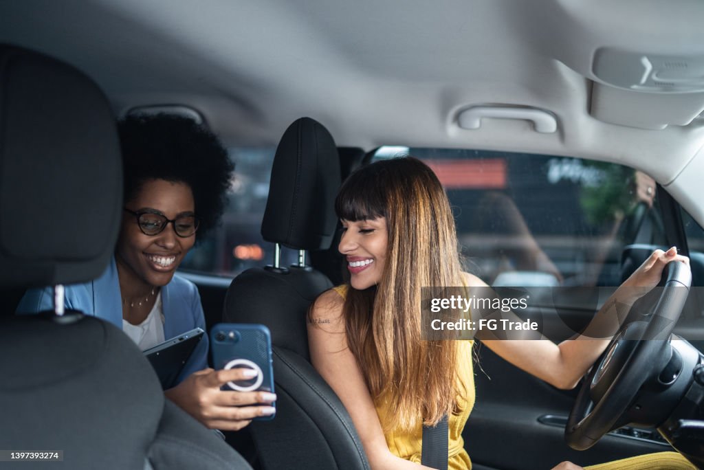 Passenger talking to cab driver and showing her the smartphone