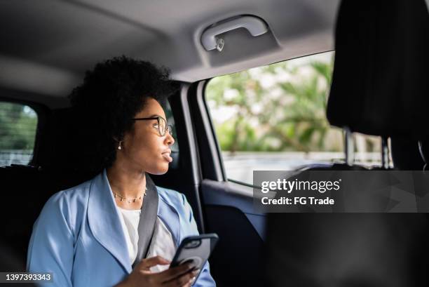 businesswoman using smartphone and looking though the window in a cab - carpool stock pictures, royalty-free photos & images