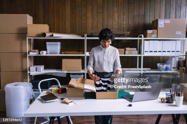 a smart businesswoman preparing packages for shipping  in her store - market trader stock pictures, royalty-free photos & images