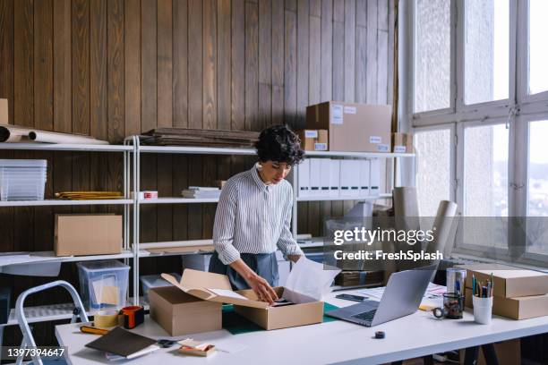 a smart businesswoman preparing packages for shipping  in her store - online business stock pictures, royalty-free photos & images