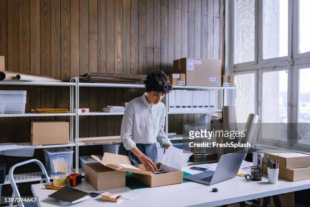 a smart businesswoman preparing packages for shipping  in her store - e commerce imagens e fotografias de stock