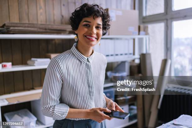 uma empresária sorridente olhando para a câmera enquanto agendava um compromisso de entrega em seu smartphone - 35 39 anos - fotografias e filmes do acervo