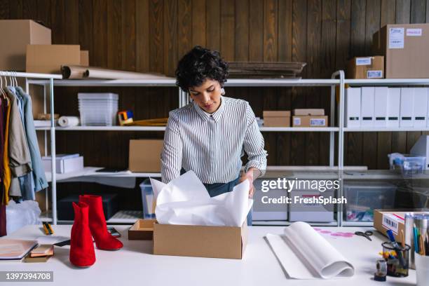 eine kluge geschäftsfrau, die ein paar rote stiefel für den versand verpackt - shoes box stock-fotos und bilder