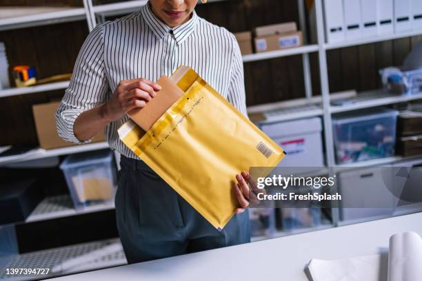 an unrecognizable businesswoman preparing a package for shipping - closing book stock pictures, royalty-free photos & images