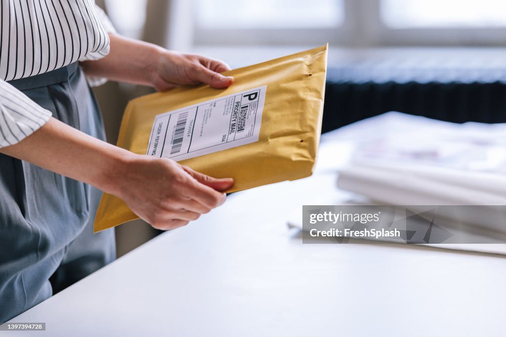 Eine nicht erkennbare Geschäftsfrau, die ein Paket für den Versand vorbereitet