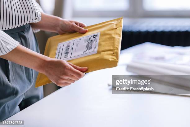 eine nicht erkennbare geschäftsfrau, die ein paket für den versand vorbereitet - postman stock-fotos und bilder