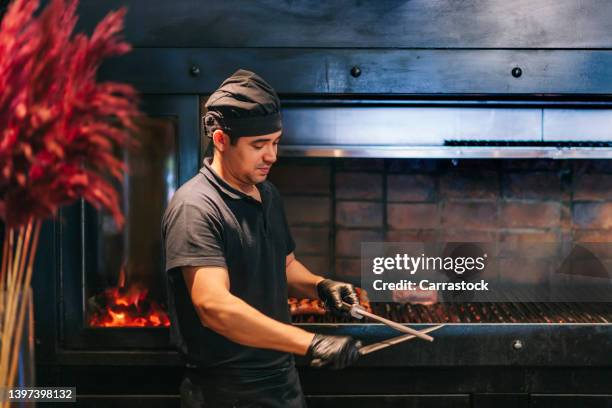 kitchen chef sharpening knife next to grill - chef coat stock pictures, royalty-free photos & images