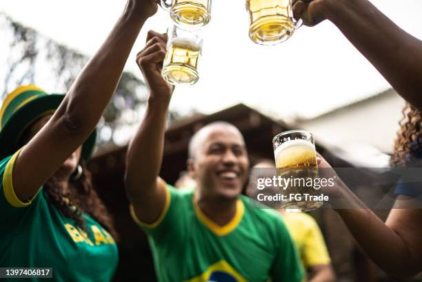 friends toasting to celebrate brazilian soccer team winning - a brazil supporter stockfoto's en -beelden