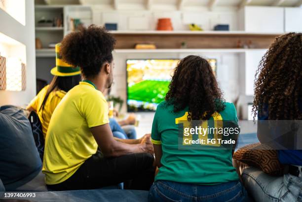 freunde, die zu hause zusammen fußballspiele schauen - female fans brazil stock-fotos und bilder
