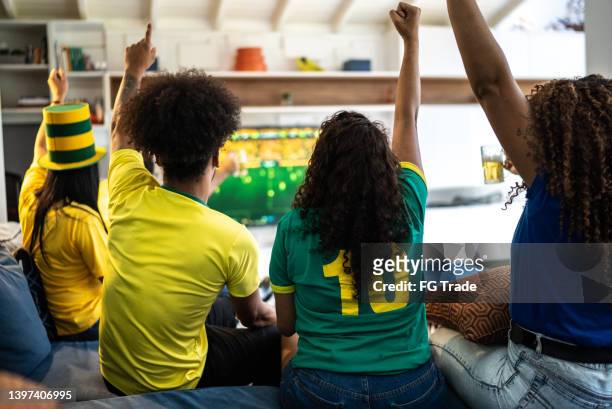 friends celebrating a goal while watching a soccer match at home - international soccer event stock pictures, royalty-free photos & images