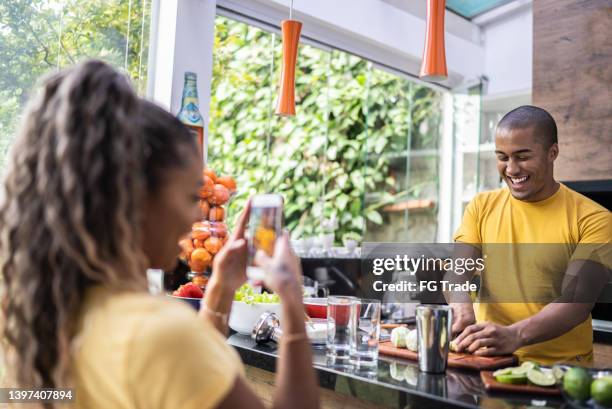 giovane donna che fotografa o filma un'amica che prepara cocktail sul barbecue a casa - caipirinha foto e immagini stock