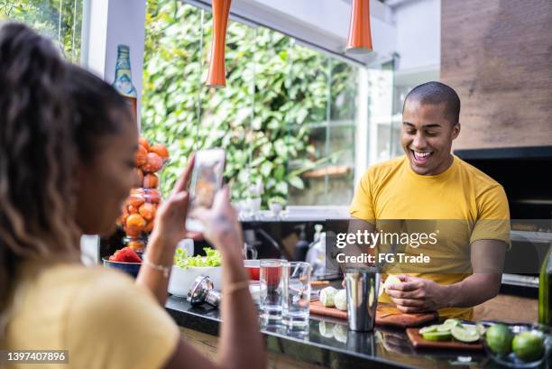 young woman photographing or filming friend preparing cocktails on barbecue at home - caipirinha stock pictures, royalty-free photos & images