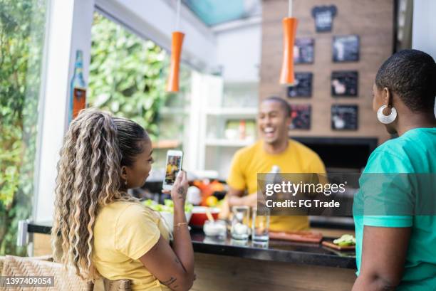 young woman photographing or filming friend preparing cocktails on barbecue at home - cachaça stock pictures, royalty-free photos & images