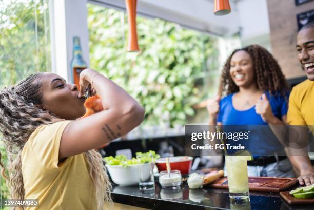 young woman drinking with friends on a barbecue at home - black shots cheers stockfoto's en -beelden