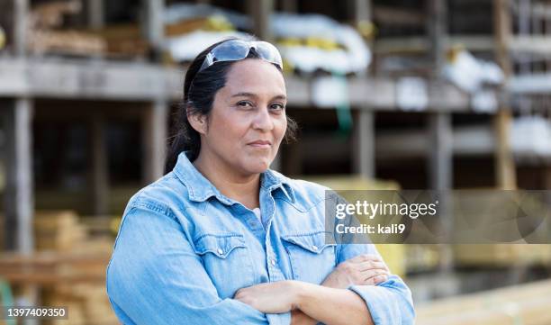 reife hispanische frau, die auf holzplatz arbeitet - hispanic construction worker stock-fotos und bilder