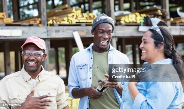 multirassische gruppe von arbeitern auf dem holzplatz, lachend - friendly small business talking stock-fotos und bilder