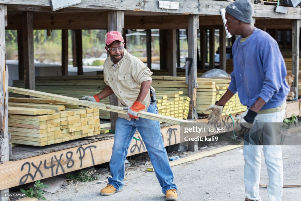 Two African-American men stacking wood at lumberyard