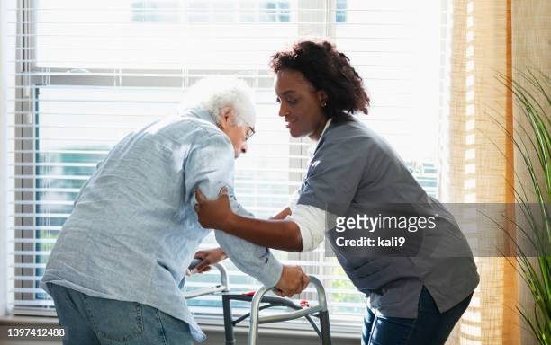 home healthcare worker helps senior man with walker - lifting stockfoto's en -beelden