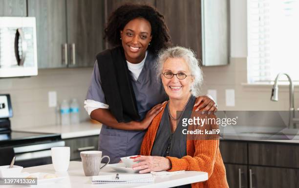 senior woman in kitchen with home caregiver - hand på axel bildbanksfoton och bilder