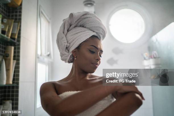 jovem aplica hidratante no corpo após banho em casa - chuveiro instalação doméstica - fotografias e filmes do acervo