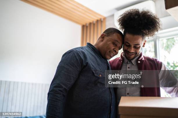 father helping son packing to move out from parent's home - proud parent stock pictures, royalty-free photos & images
