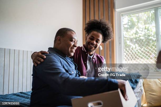 father helping son packing to move out from parent's home - man with moving boxes authentic stockfoto's en -beelden
