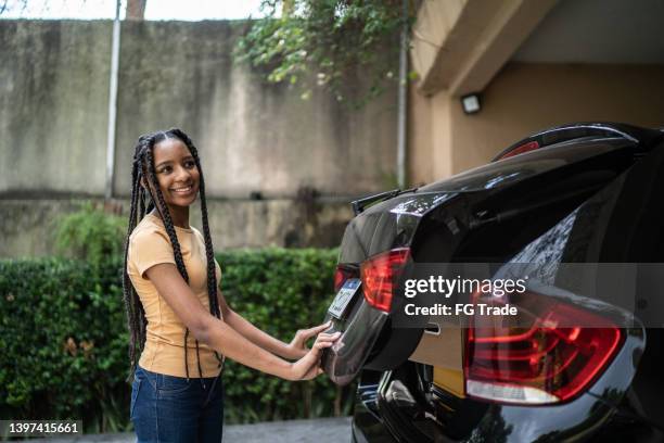 teenage girl closing car trunk door - closing door stock pictures, royalty-free photos & images